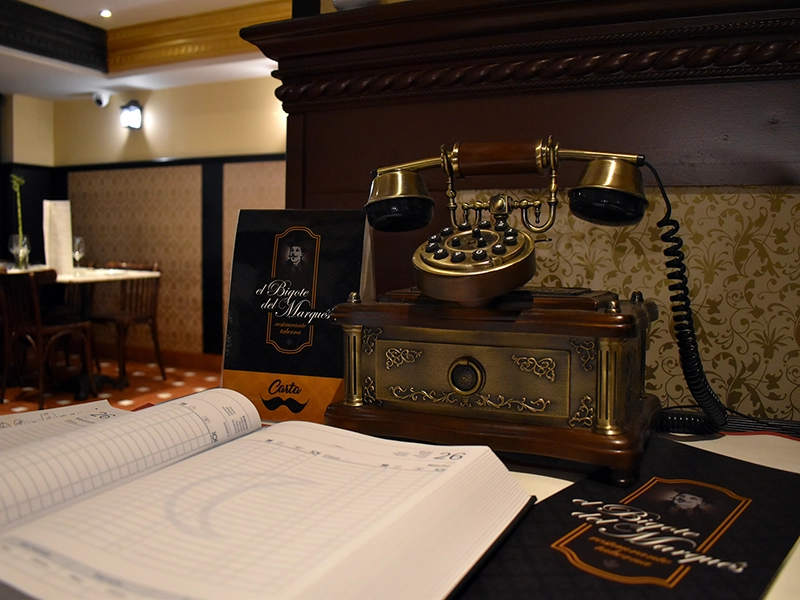 Primer plano de teléfono antiguo y agenda de comidas de El Bigote del Marqués.