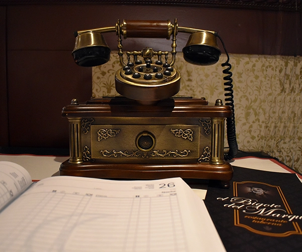 Primer plano de teléfono antiguo y agenda de comidas de El Bigote del Marqués.